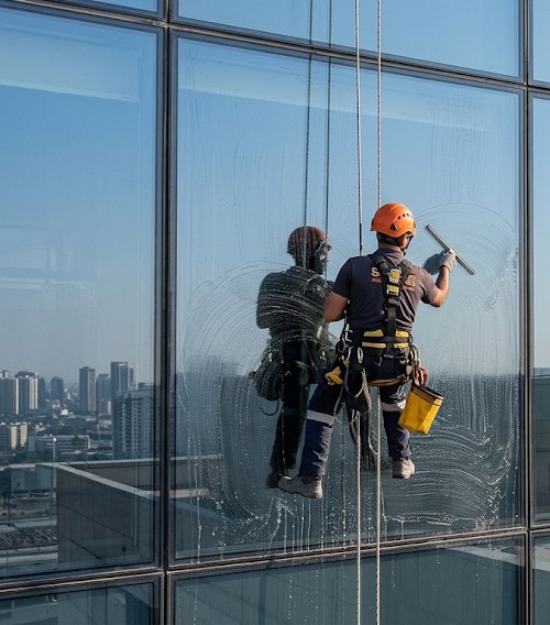 A rope access technician cleaning a high rise glass facade